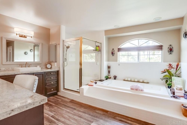 full bathroom with a bath, a shower stall, vanity, and wood finished floors