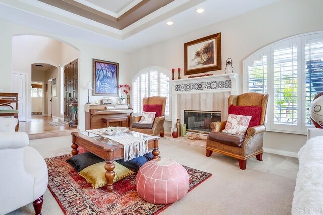 living area with baseboards, recessed lighting, arched walkways, a glass covered fireplace, and a raised ceiling