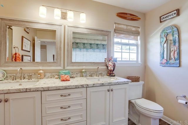 bathroom featuring double vanity, toilet, and a sink