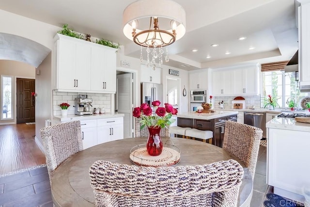 dining space with a raised ceiling, a notable chandelier, and recessed lighting