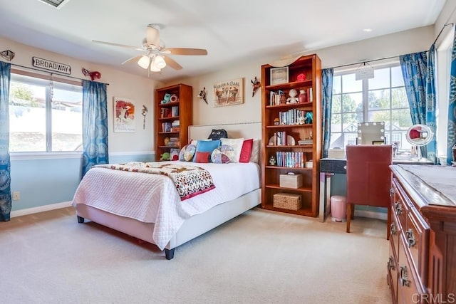 bedroom featuring baseboards, multiple windows, light colored carpet, and a ceiling fan