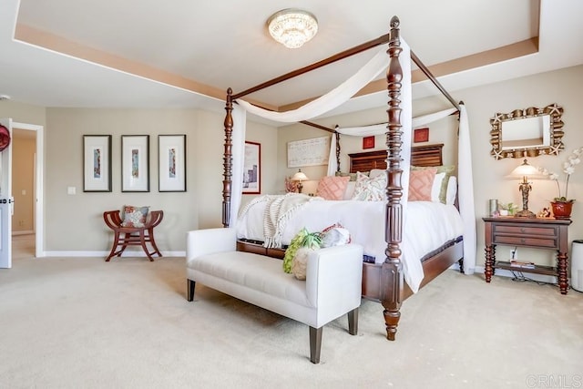 carpeted bedroom with baseboards and a tray ceiling