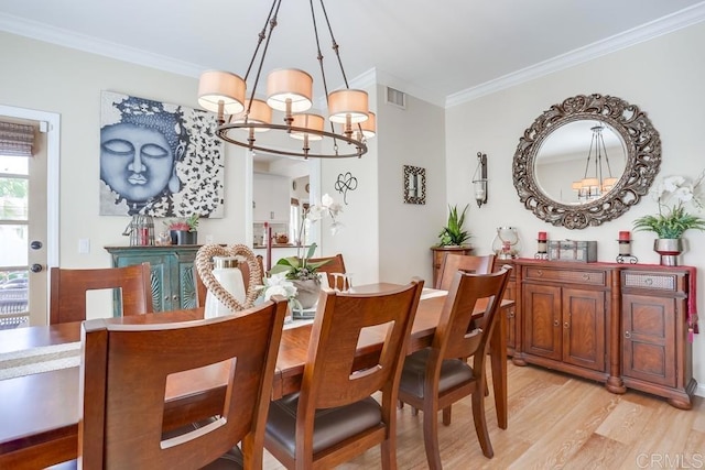 dining area with a notable chandelier, visible vents, crown molding, and light wood-type flooring