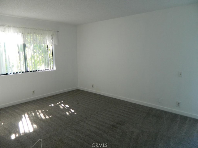 spare room featuring carpet flooring and baseboards