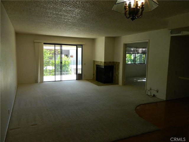 unfurnished living room with a textured ceiling, carpet flooring, a multi sided fireplace, and plenty of natural light