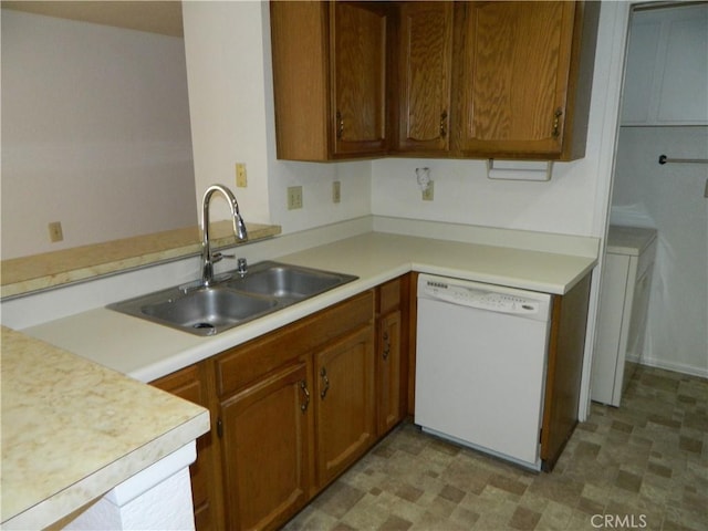 kitchen with light countertops, brown cabinets, white dishwasher, and a sink