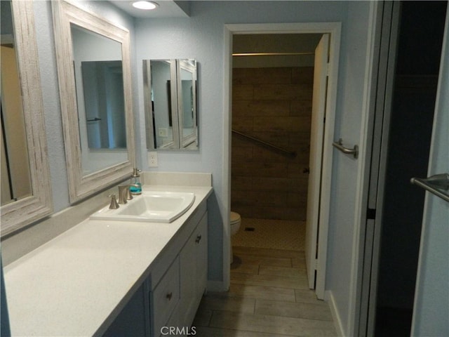 bathroom with tiled shower, toilet, and vanity