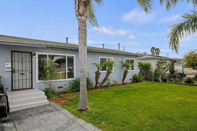 back of house featuring crawl space, stucco siding, a lawn, and fence