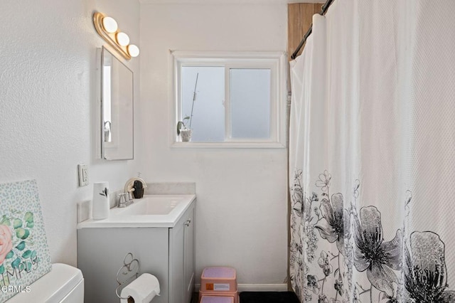 bathroom featuring curtained shower, toilet, and vanity