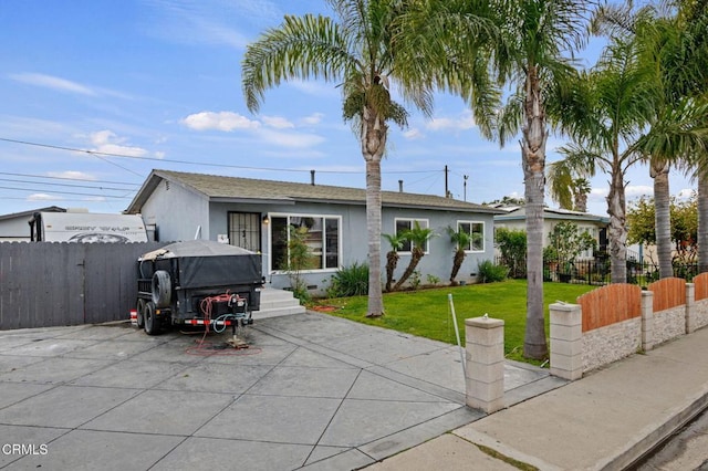 back of house featuring stucco siding, driveway, a yard, and fence