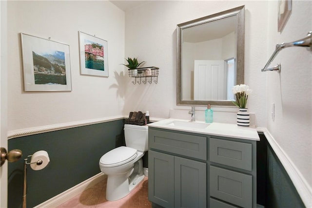 half bathroom with vanity, toilet, and tile patterned flooring