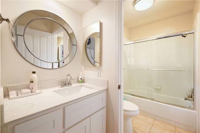 bathroom featuring tile patterned flooring, toilet, vanity, and combined bath / shower with glass door