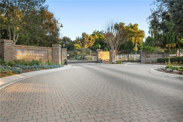 view of street featuring curbs, a gated entry, street lighting, and a gate