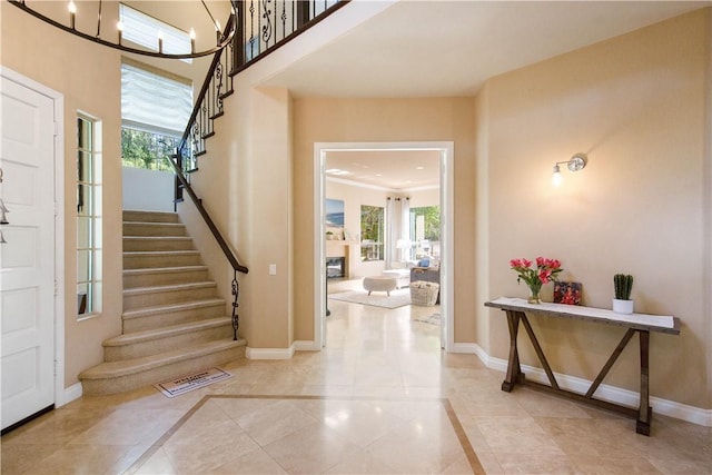 entryway featuring stairs, a glass covered fireplace, visible vents, and baseboards