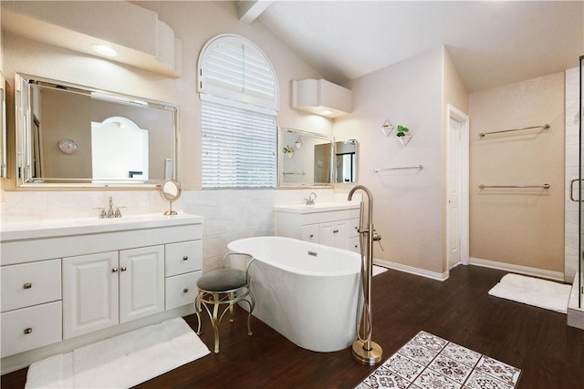 bathroom featuring vaulted ceiling, a freestanding tub, wood finished floors, and a sink