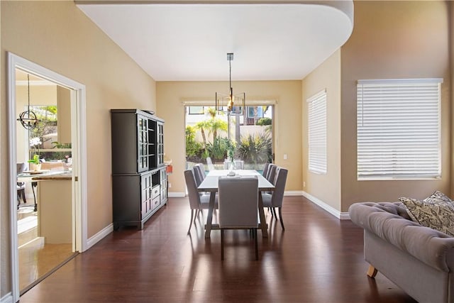 dining room with a chandelier, dark wood-type flooring, and baseboards