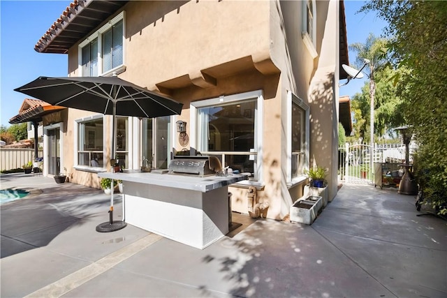 view of patio with a grill, fence, and an outdoor kitchen