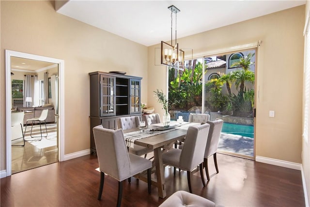 dining room featuring a notable chandelier, baseboards, and wood finished floors