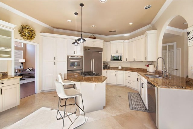 kitchen with a sink, a kitchen bar, built in appliances, and dark stone counters