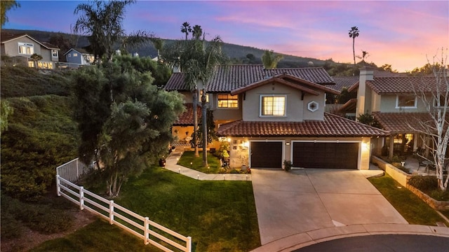 mediterranean / spanish house with driveway, a tile roof, a front yard, and fence