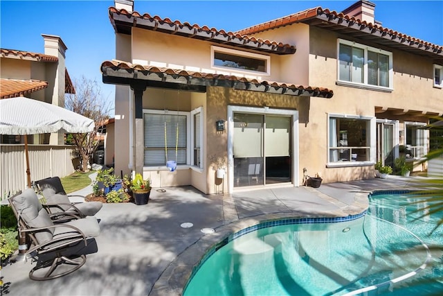 back of property featuring a fenced in pool, a patio area, fence, and stucco siding