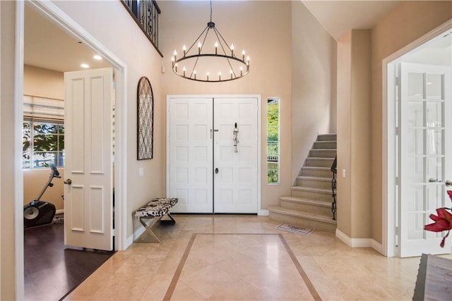 entryway with stairs, a high ceiling, baseboards, and a chandelier