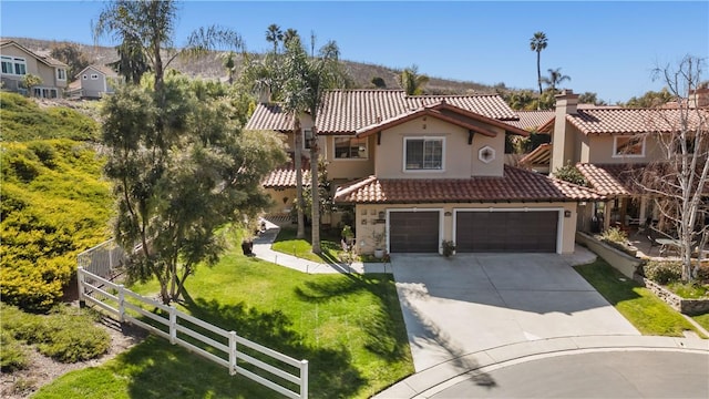 mediterranean / spanish home with stucco siding, driveway, fence, a garage, and a tiled roof