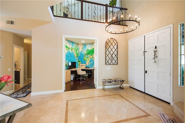 entryway featuring a notable chandelier, visible vents, a high ceiling, and baseboards