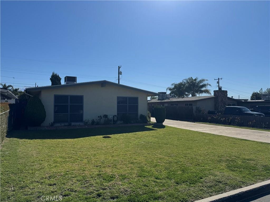 view of front of property featuring stucco siding, a front yard, driveway, and fence