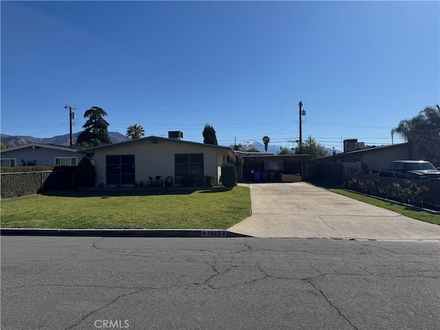 ranch-style house with stucco siding, driveway, a front lawn, and fence