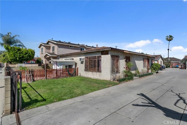 exterior space with stucco siding, a yard, and fence