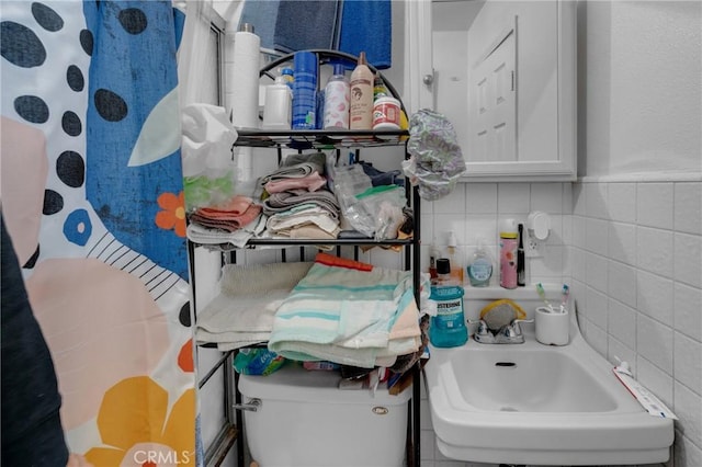 bathroom with tile walls, toilet, and a sink