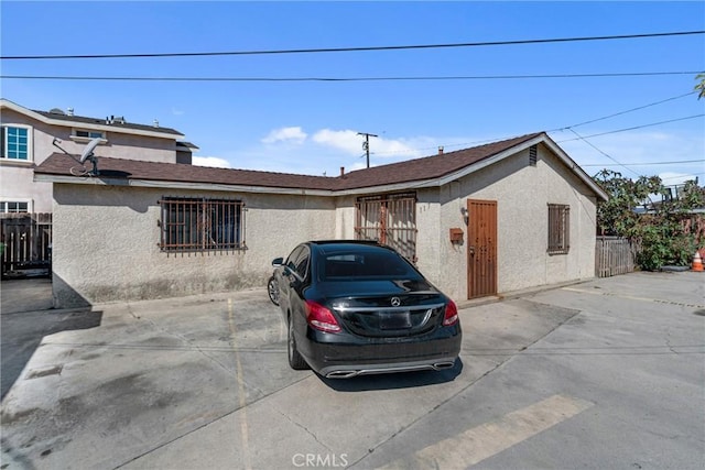 view of front facade with stucco siding and fence