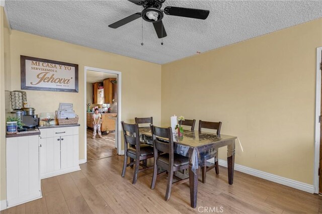 dining area featuring light wood-style floors, baseboards, and a textured ceiling