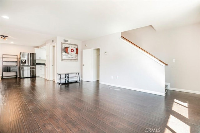 unfurnished living room with visible vents, baseboards, dark wood-type flooring, and stairway