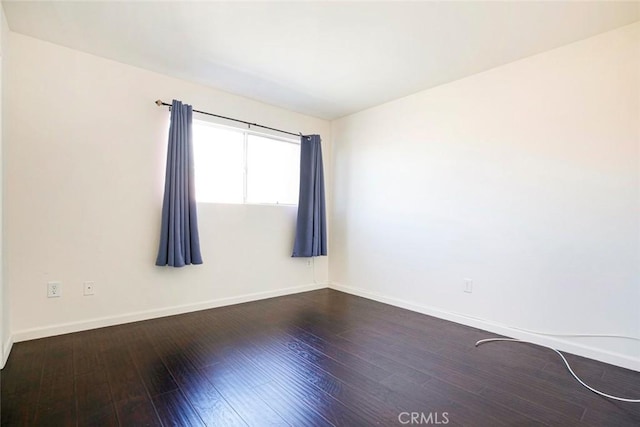 unfurnished room featuring dark wood-type flooring and baseboards