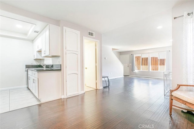 kitchen featuring dark countertops, visible vents, baseboards, open floor plan, and wood finished floors