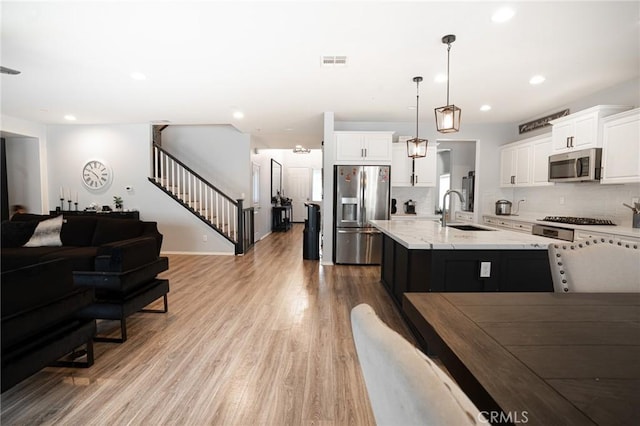 kitchen featuring wood finished floors, visible vents, a sink, stainless steel appliances, and open floor plan