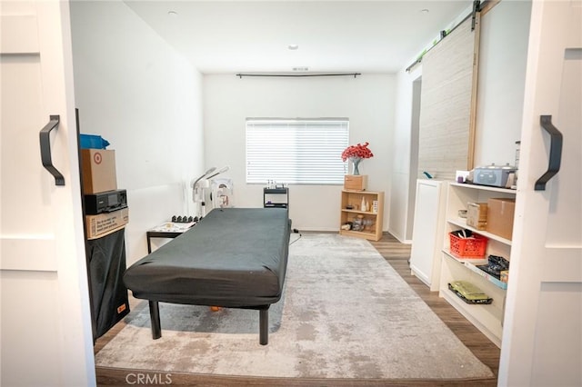 bedroom with a barn door and wood finished floors