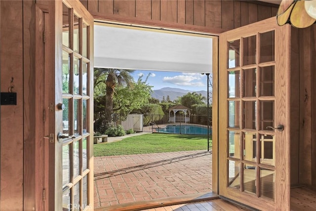 doorway to outside featuring brick floor, a mountain view, wooden walls, and french doors