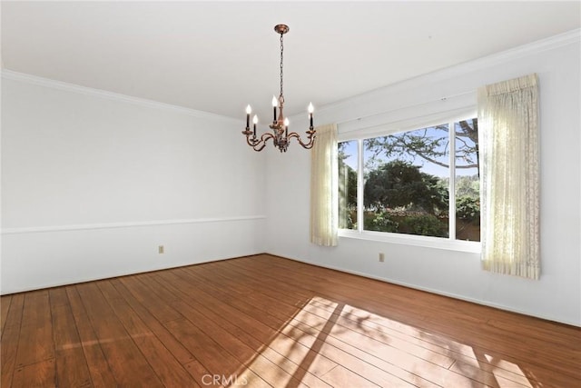 spare room with hardwood / wood-style floors, ornamental molding, and a chandelier