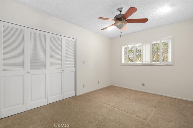 unfurnished bedroom with a ceiling fan, baseboards, a closet, a textured ceiling, and carpet flooring