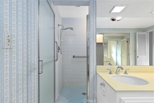 bathroom featuring vanity, a stall shower, and a textured ceiling