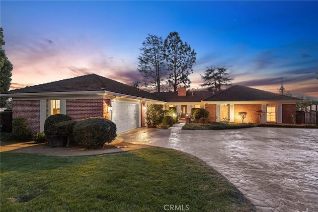 ranch-style home with brick siding, an attached garage, decorative driveway, and a front lawn