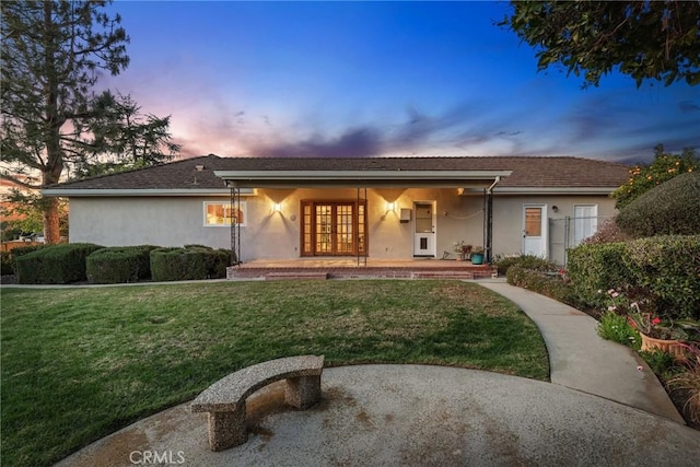 ranch-style home with french doors, a lawn, and stucco siding