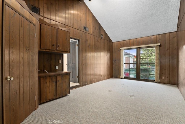 interior space featuring wood walls, a textured ceiling, and high vaulted ceiling