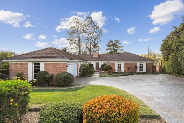 ranch-style house with concrete driveway, an attached garage, brick siding, and a front yard