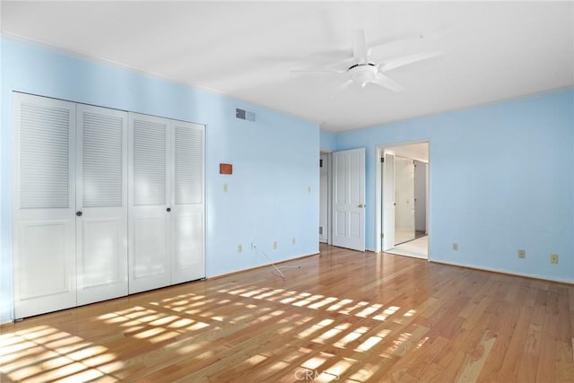 unfurnished bedroom featuring visible vents, a ceiling fan, wood finished floors, and ensuite bathroom