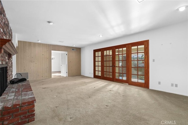 unfurnished living room featuring visible vents, a fireplace, french doors, and carpet floors