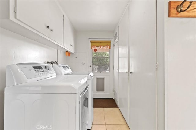 laundry room with cabinet space, light tile patterned flooring, and washing machine and clothes dryer